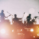 Concert of a musical rock band. Silhouettes of musicians on a set background.