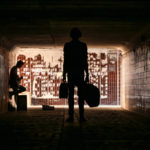 Two street musicians in the underpass. Silhouette photo.