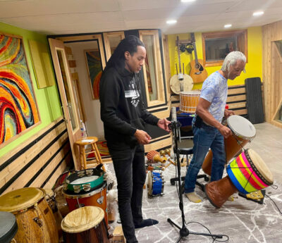 A photo of engineer and mixer Darren Moore with Bashiri Johnson setting up a percussion recording session.